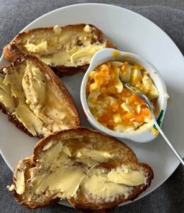 Loads of butter on tiger toast with mashed egg in a cup