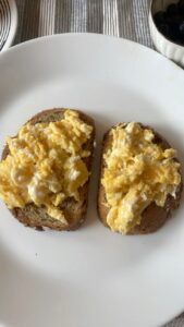Loads of butter on tiger toast with mashed egg in a cup